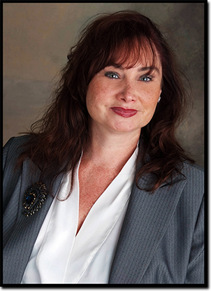 A woman with long hair and blue eyes wearing a suit.